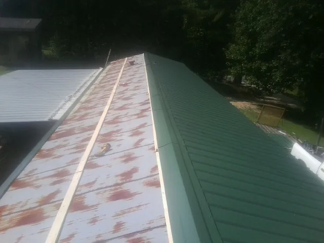 Old rusted panels beside newly installed green metal roofing — Wind Damage Roof Repair by Roofing Brothers in Collierville