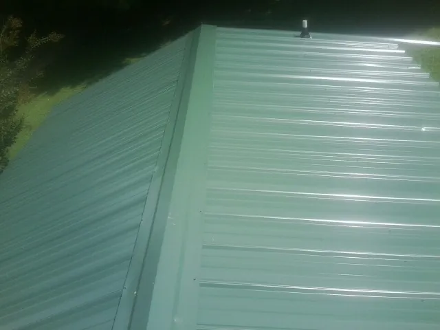 New green metal panels meeting at the ridge of a roof — Flat Roof Repair work by our crew in Collierville