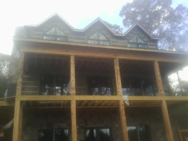 Dormers and porch framing on a large log home under construction — Roof Coating work by our crew in Collierville
