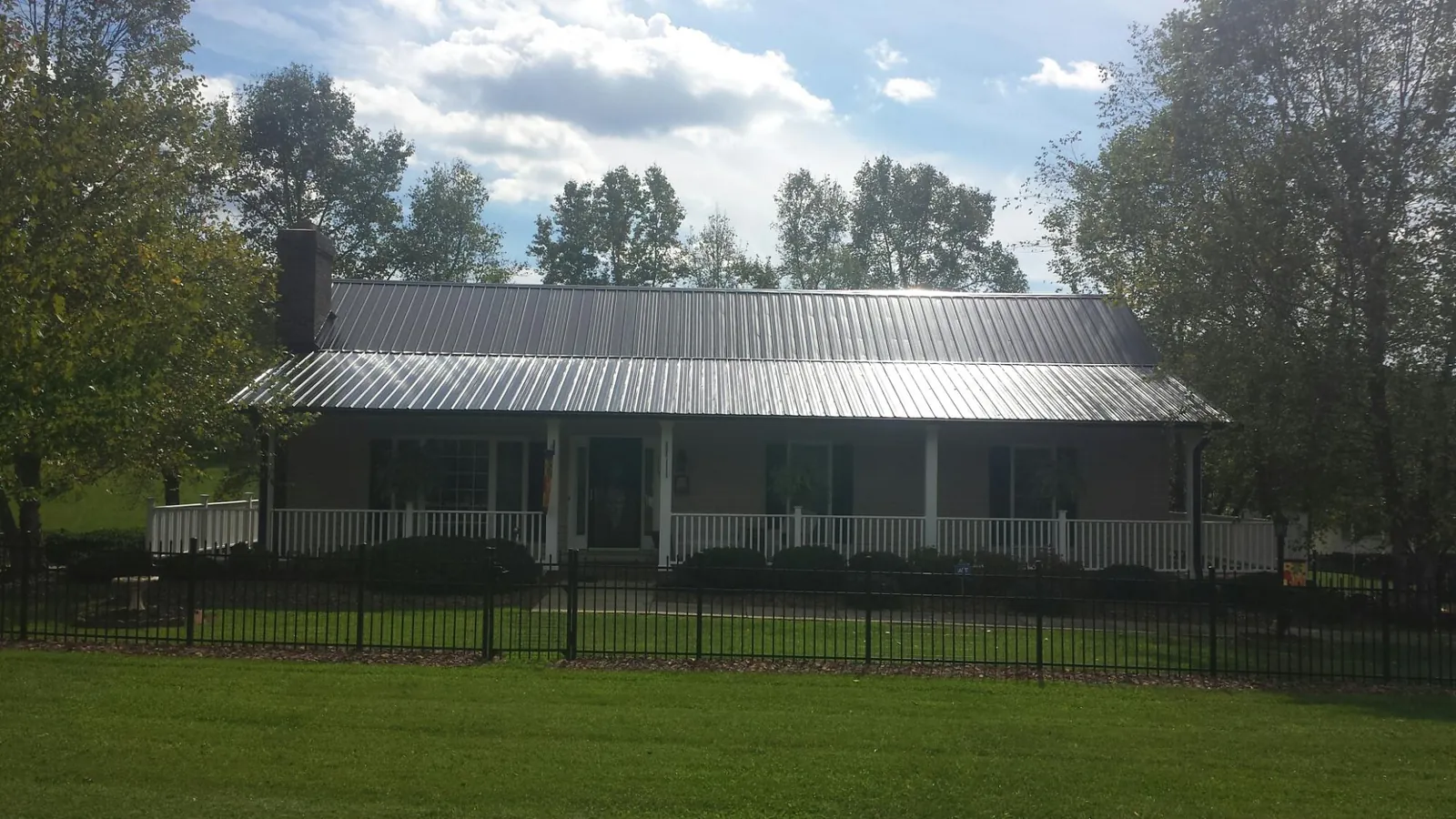 Gray metal roof on a brick ranch with a full width front porch — Gutter Guard Installation work by our crew in Collierville