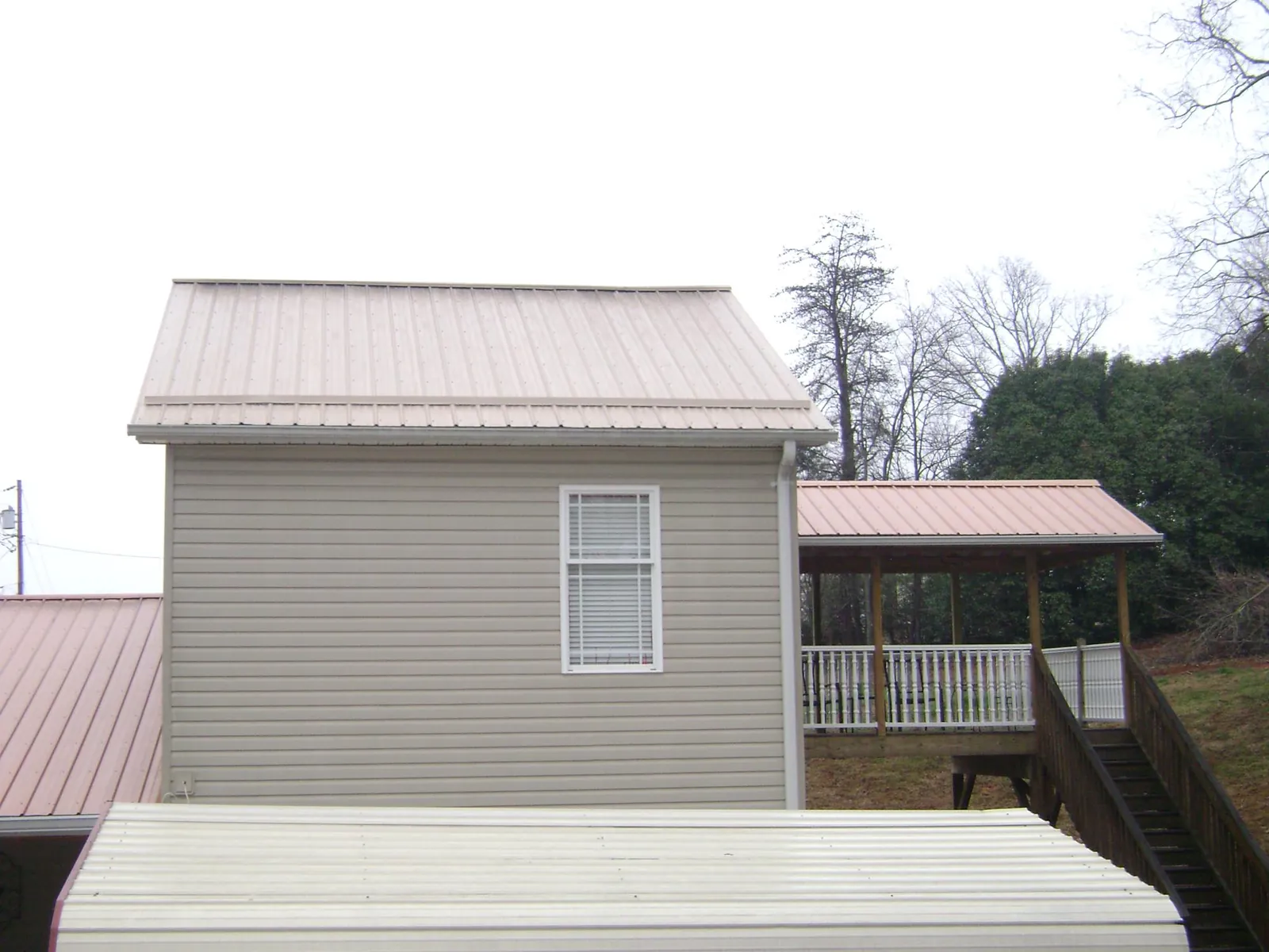 Tan metal roofs on a two story addition and attached porch, from a Roof Replacement job in Collierville