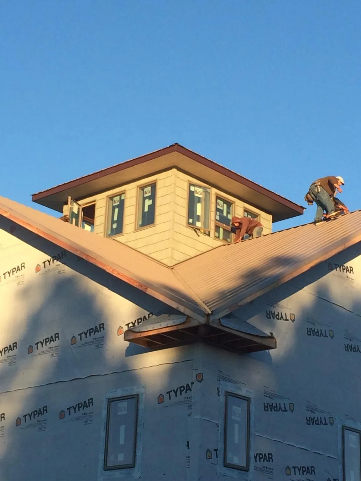 Roofers working around a rooftop cupola on a new metal roof at sunset — Roof Waterproofing in Collierville by Roofing Brothers